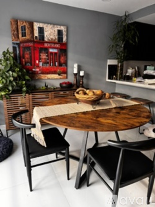 A dining table with a woven placemat and a basket of bread on it.