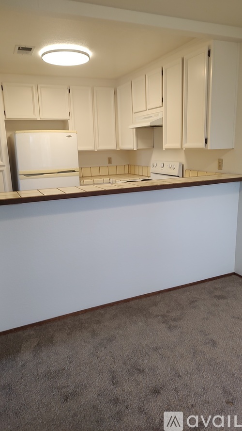 A kitchen with white cabinets and a white refrigerator.