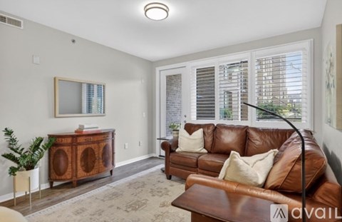 A living room with a brown leather couch and a wooden cabinet.