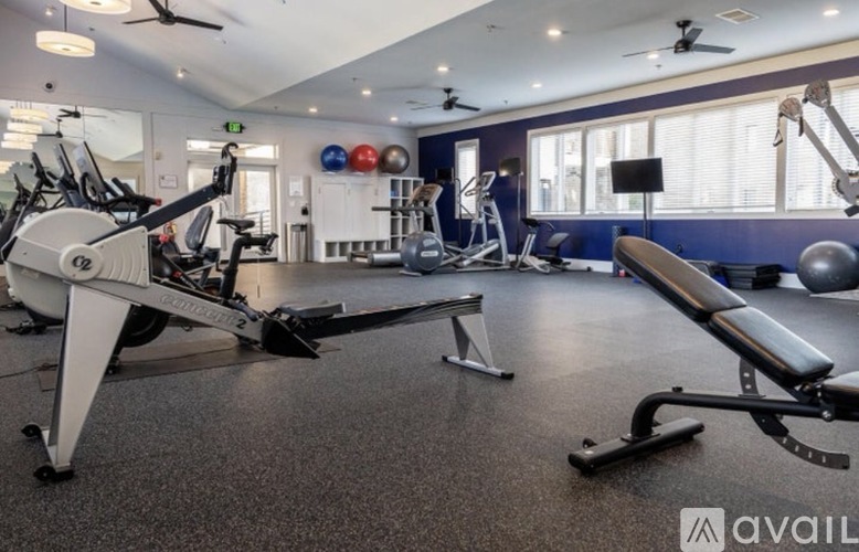 A gym with a variety of equipment including a rowing machine, a bench, and a mirror.