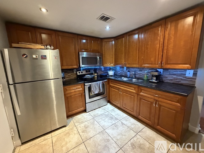 A kitchen with wooden cabinets and a stainless steel refrigerator.