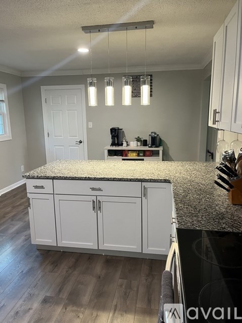A kitchen with white cabinets and a granite countertop.