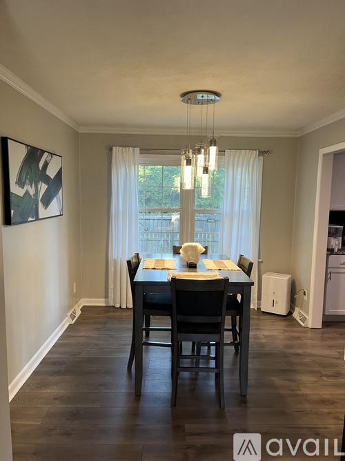 A dining room with a table set for two and a chandelier hanging from the ceiling.