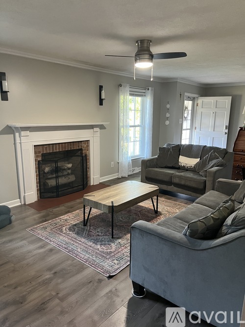 A living room with a fireplace and a grey couch.