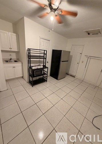 A kitchen with a black fridge and a fan on the ceiling.