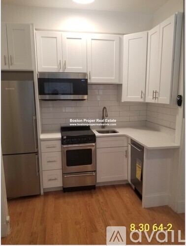 A kitchen with white cabinets and a stainless steel refrigerator.