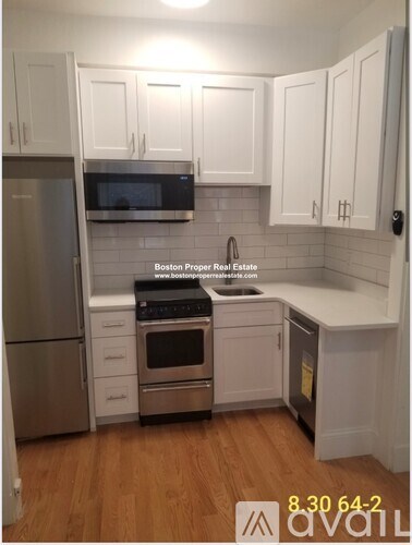 A kitchen with white cabinets and a stainless steel refrigerator.