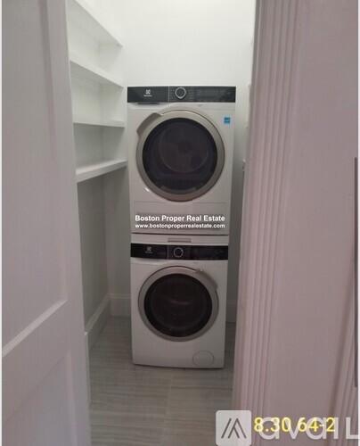 A washing machine in a laundry room with a sign that says Boston Proper Real Estate.
