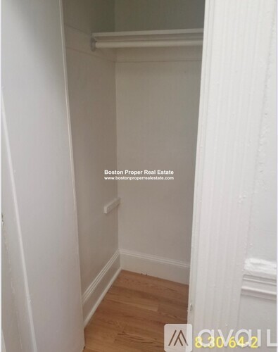 A small, empty room with wooden flooring and white walls.