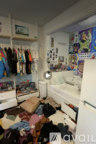A room with a white refrigerator and a wall covered in posters and drawings.