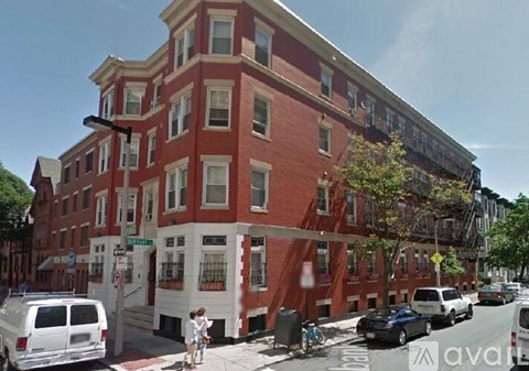 A street view of a red brick building with a white van parked in front.