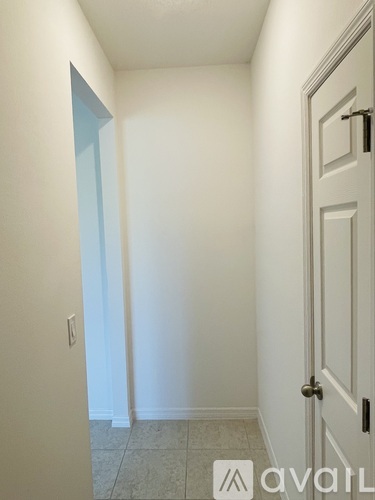A hallway with a door on the right and a light switch on the wall.