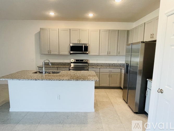 A kitchen with white cabinets and a granite countertop.