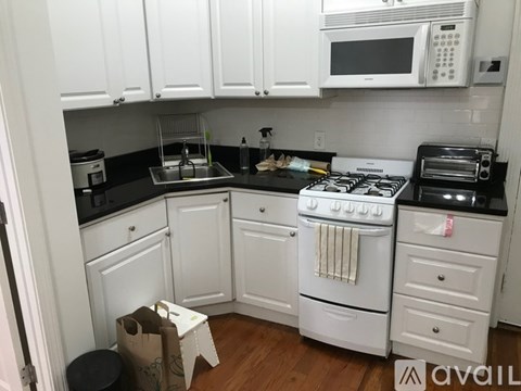 A kitchen with white cabinets and a black stove top.