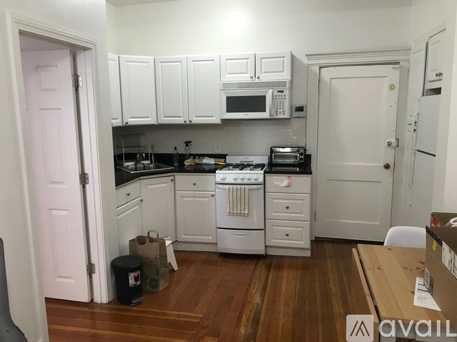 A kitchen with white cabinets and appliances is available for rent.