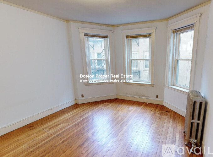 A room with wooden floors and two windows.