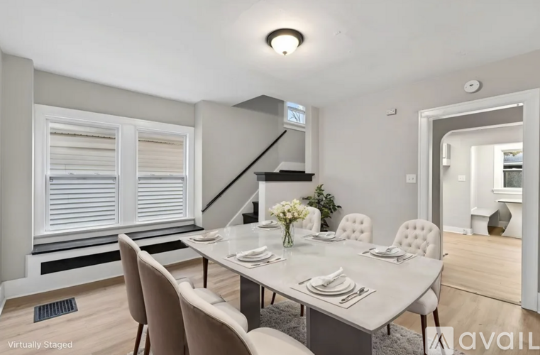 A dining room with a table set for six and a staircase in the background.