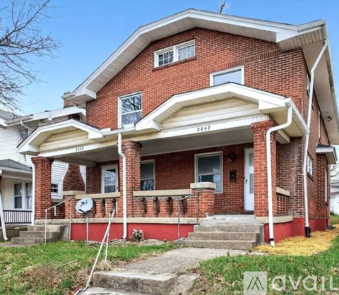 A red brick house with a white porch and a white door.