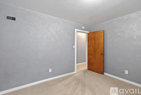 A room with a wooden door and a light switch on the wall.