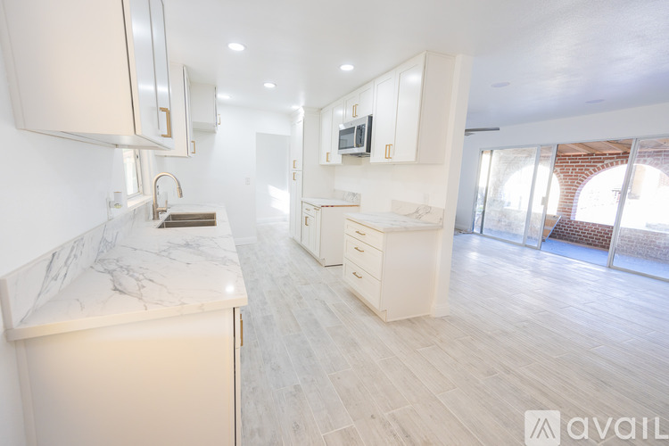 A modern kitchen with white cabinets and a marble countertop.