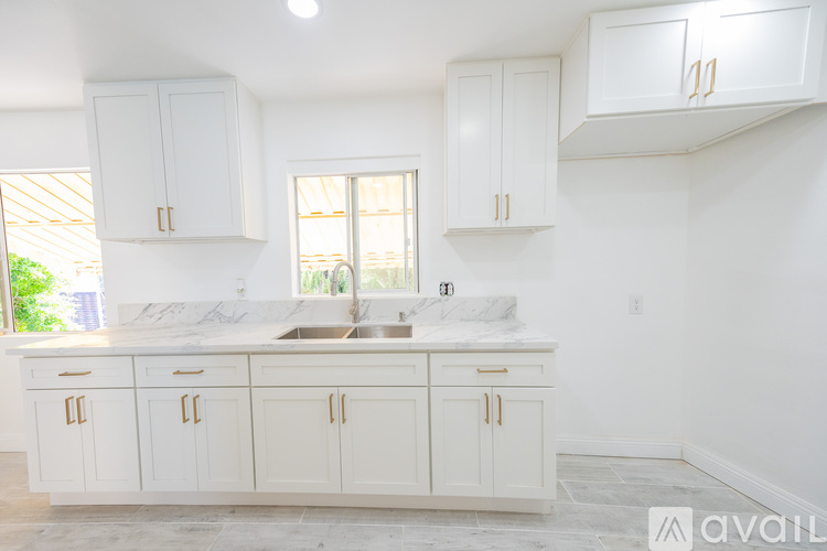 A kitchen with white cabinets and a marble countertop.