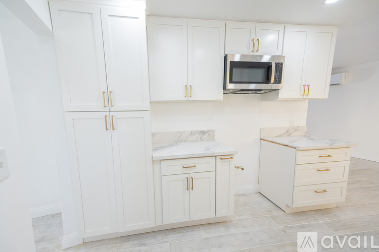A kitchen with white cabinets and a microwave above the counter.