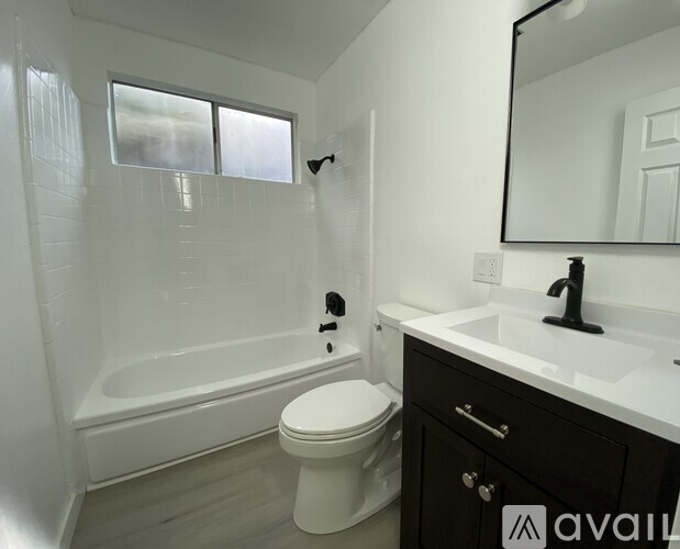 A white toilet sits in a bathroom next to a bathtub and sink.