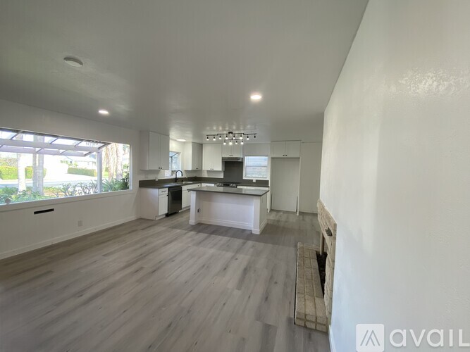 A spacious kitchen with white cabinets and a dining area with a table and chairs.