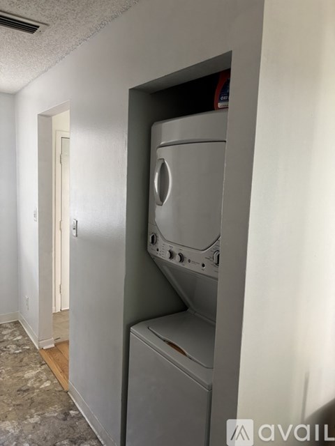 A grey washing machine is in a small room.