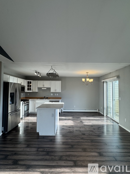 A kitchen with white appliances and a wooden floor.