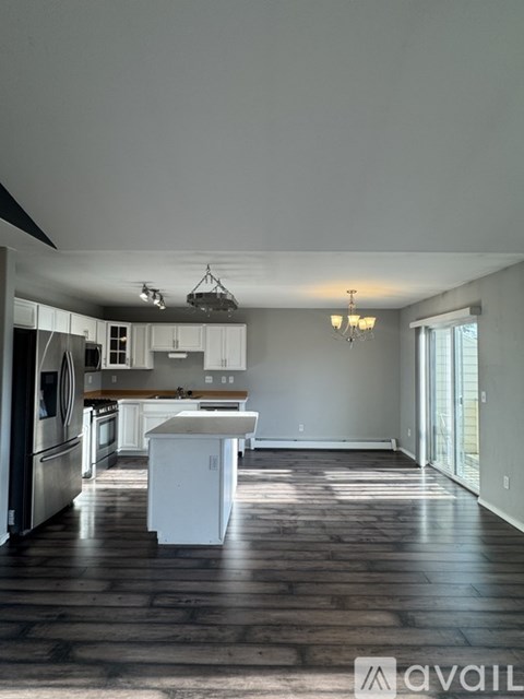 A kitchen with white appliances and a wooden floor.