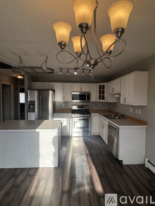 A kitchen with a chandelier and wooden floors.