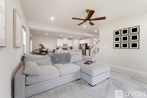 A living room with a grey couch and a ceiling fan.