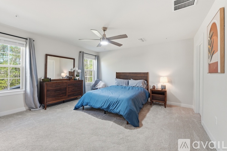 A bedroom with a blue bedspread and a ceiling fan.