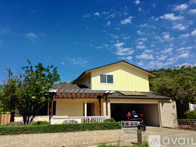 A yellow house with a garage and a car parked inside.