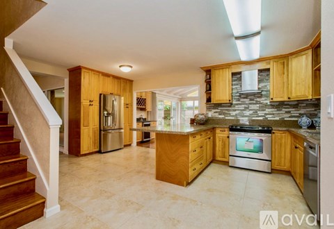 A kitchen with wooden cabinets and a stone backsplash is available for rent.