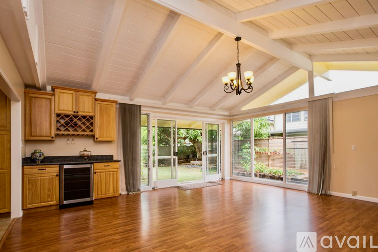 A kitchen with wooden cabinets and a black countertop with a chandelier hanging from the ceiling.