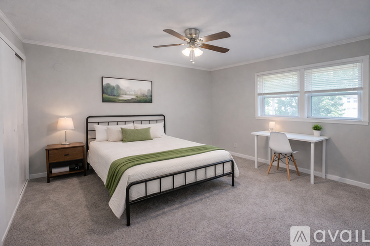 A bedroom with a bed, desk, and window.