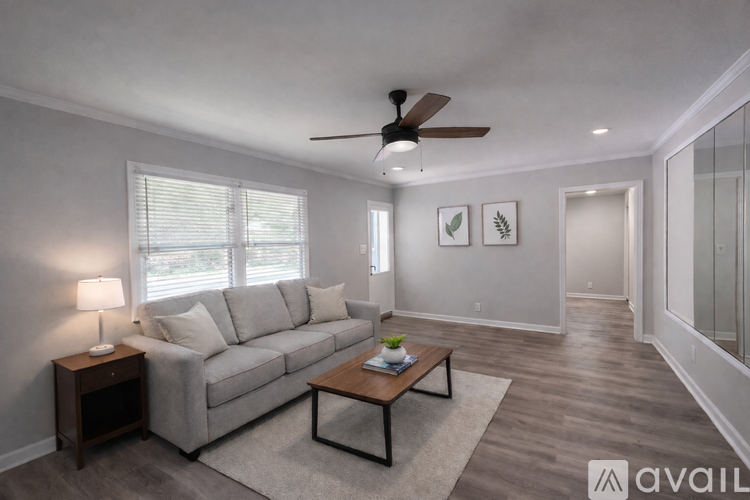 A living room with a grey couch, a wooden coffee table, and a ceiling fan.