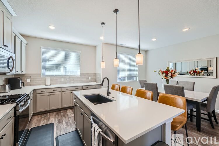 A modern kitchen with a large island and brown chairs.