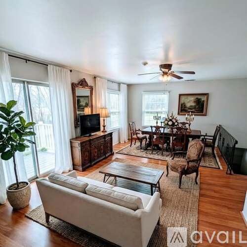 A living room with a white sofa, wooden coffee table, and a television.