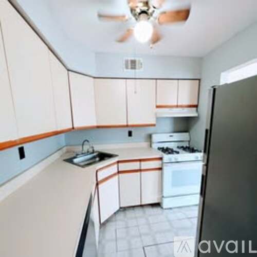 A kitchen with white cabinets and a black refrigerator.