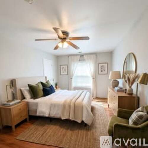 A bedroom with a bed, a chair, and a ceiling fan.