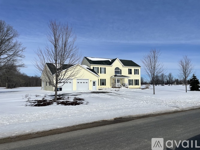 A house with a white garage door is surrounded by snow.