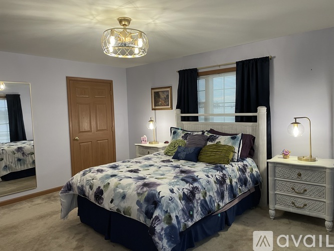 A bedroom with a large bed and a chandelier hanging from the ceiling.