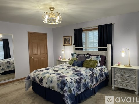 A bedroom with a large bed and a chandelier hanging from the ceiling.