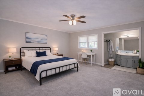 A bedroom with a large bed and a bathroom with a sink and mirror.