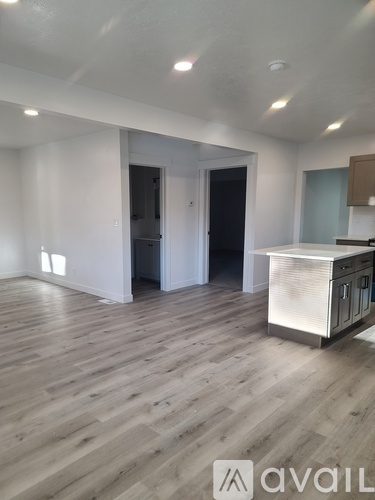 A spacious room with wooden flooring and a kitchen island in the corner.