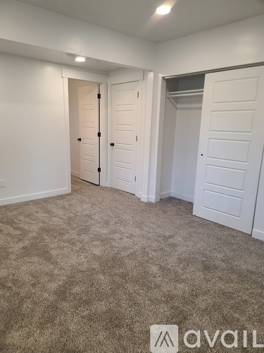 A room with carpeted floor and two doors.