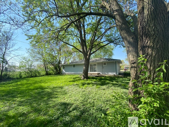 A house is surrounded by a grassy lawn and trees.